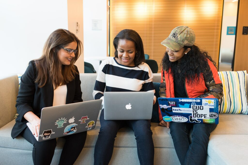 Drei Frauen unterschiedlicher Hautfarben vor Laptops.