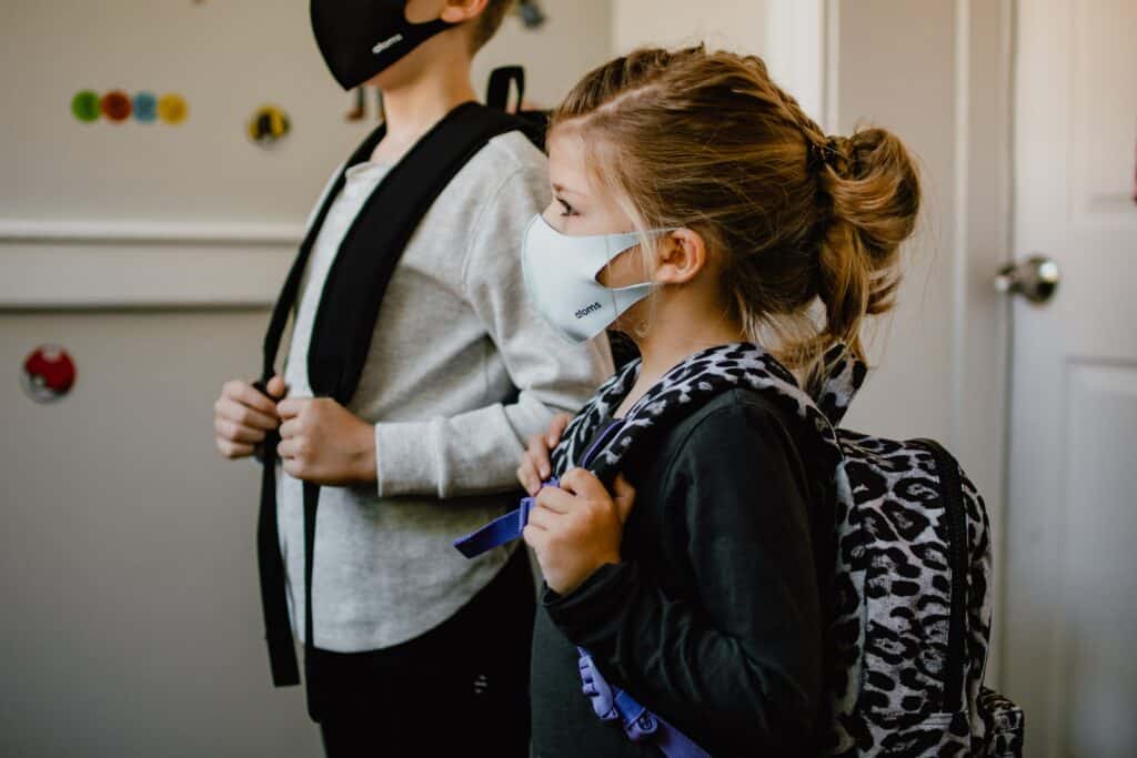 Kinder mit Mund-Nase-Schutz und Schulranzen Ruf nach Bildung