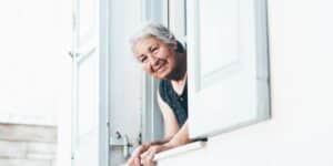 Rentnerin schaut aus Fenster raus