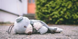 Gewalt in Kindertagesstätten. Ein beschädigter Teddybär liegt auf dem Boden