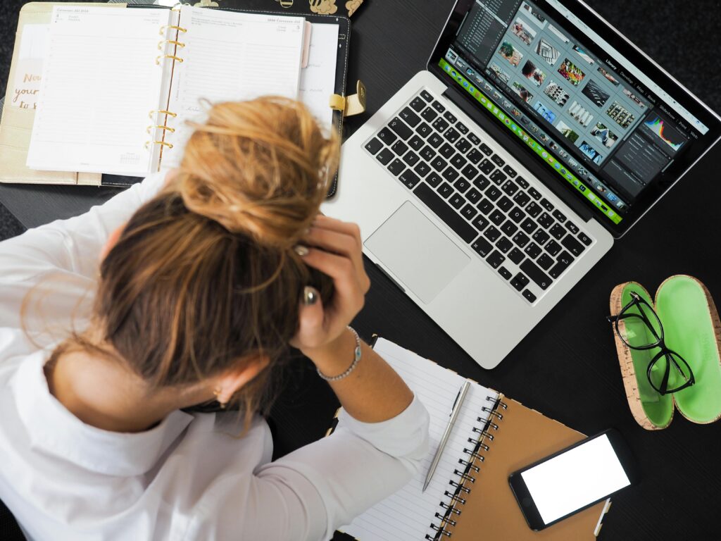 Frau an Schreibtisch legt Kopf auf den Tisch. Missbrauch von wissenschaftlichen Publikationen.