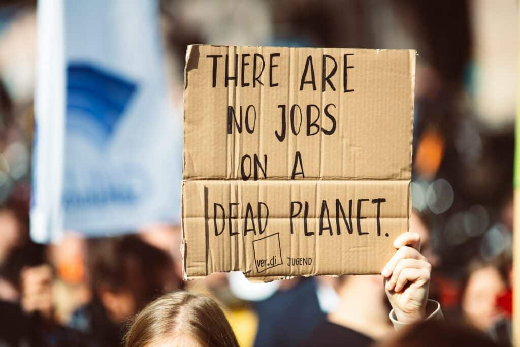 Mensch auf Demonstation hält ein Schild mit Aufschrift "There are no Jobs on a Dead Planet" hoch. Klimaschutz