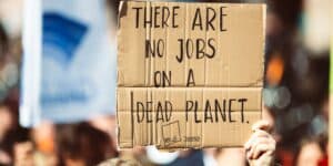 Mensch auf Demonstation hält ein Schild mit Aufschrift "There are no Jobs on a Dead Planet" hoch. Klimaschutz