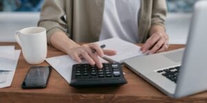 Person rechnet mit einem Taschenrechner. Bücher kalkulieren